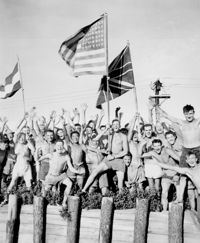 Liberated Allied POWs  cheer and wave their countries' flags at Yokohama